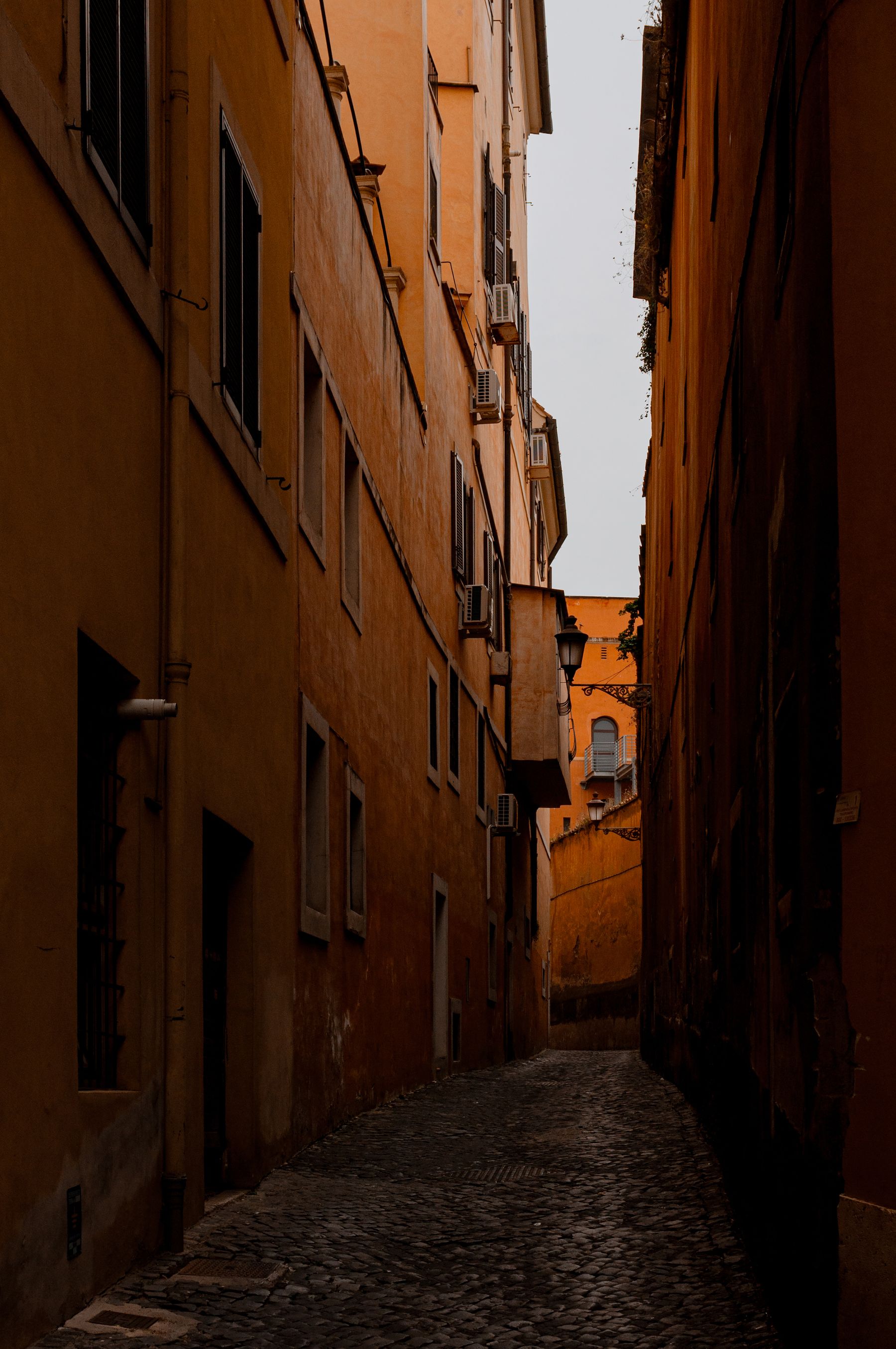 A quiet cobbled lane between ochre buildings in Rome, Italy