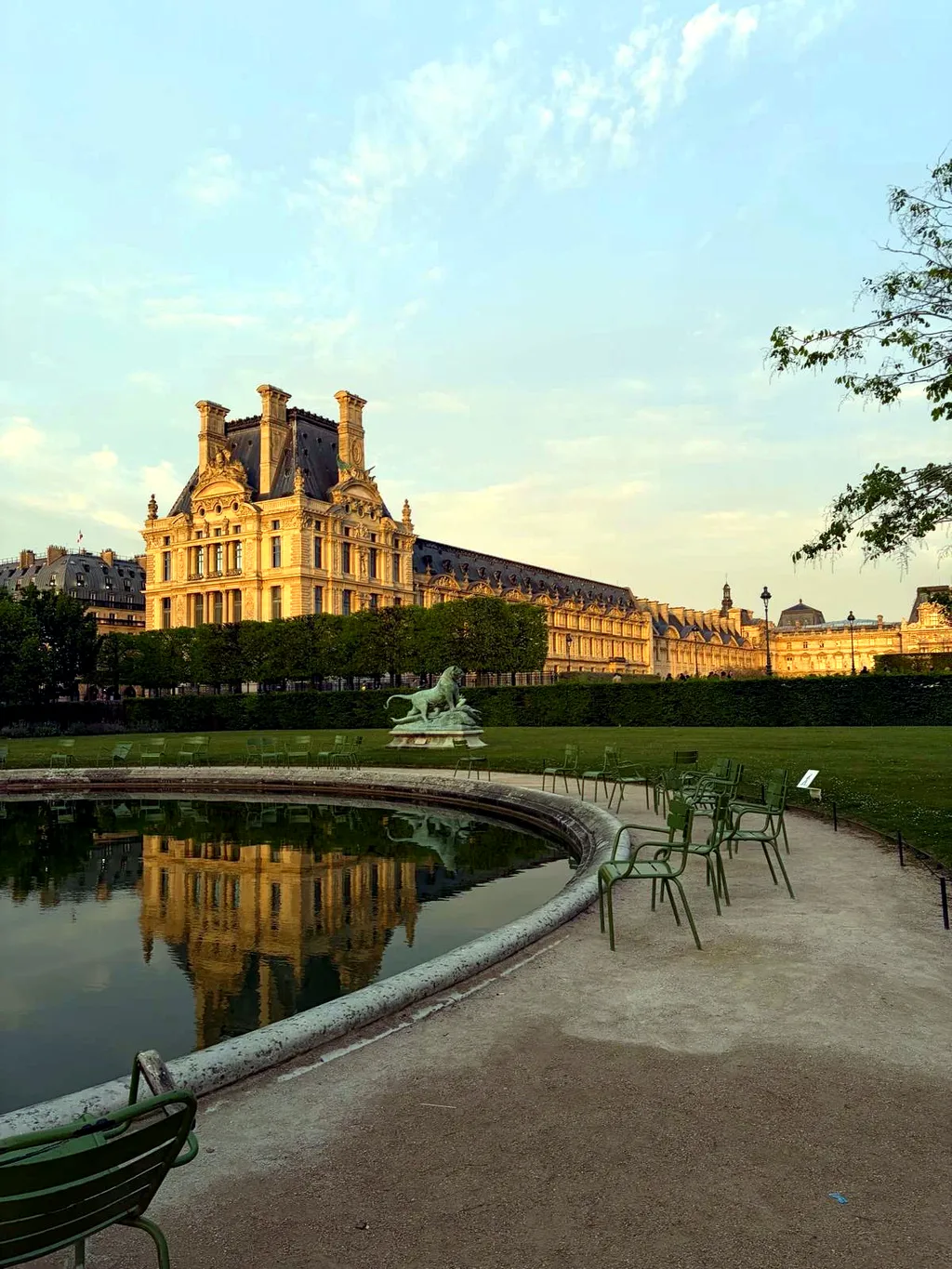 The Louvre reflected in a Tuileries garden fountain at golden hour